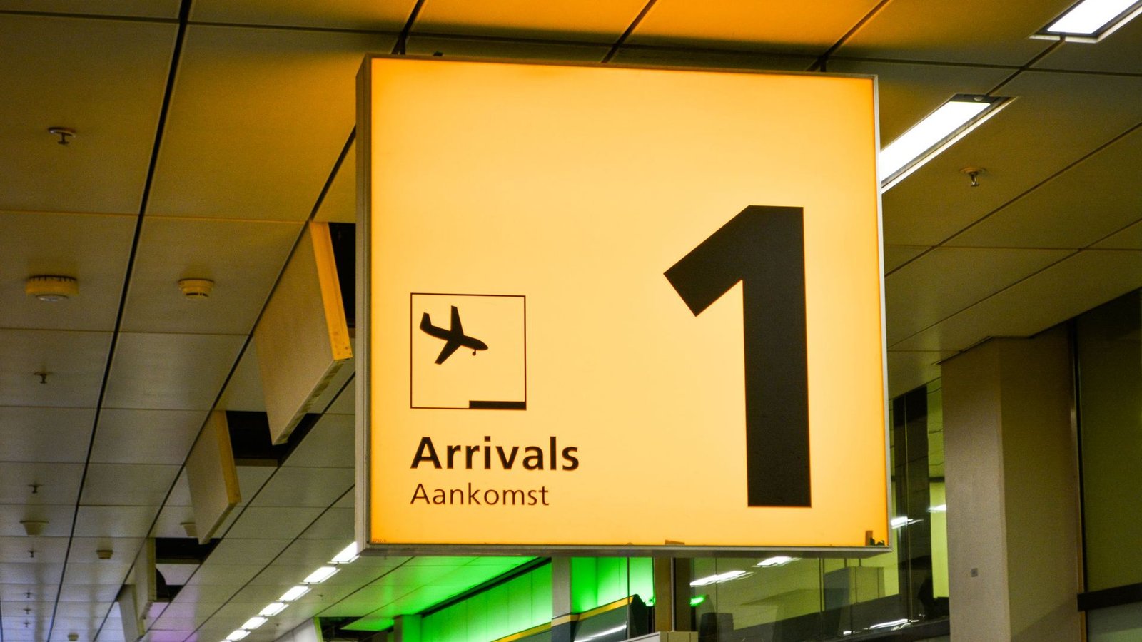 An airport arrivals sign above the terminal exit