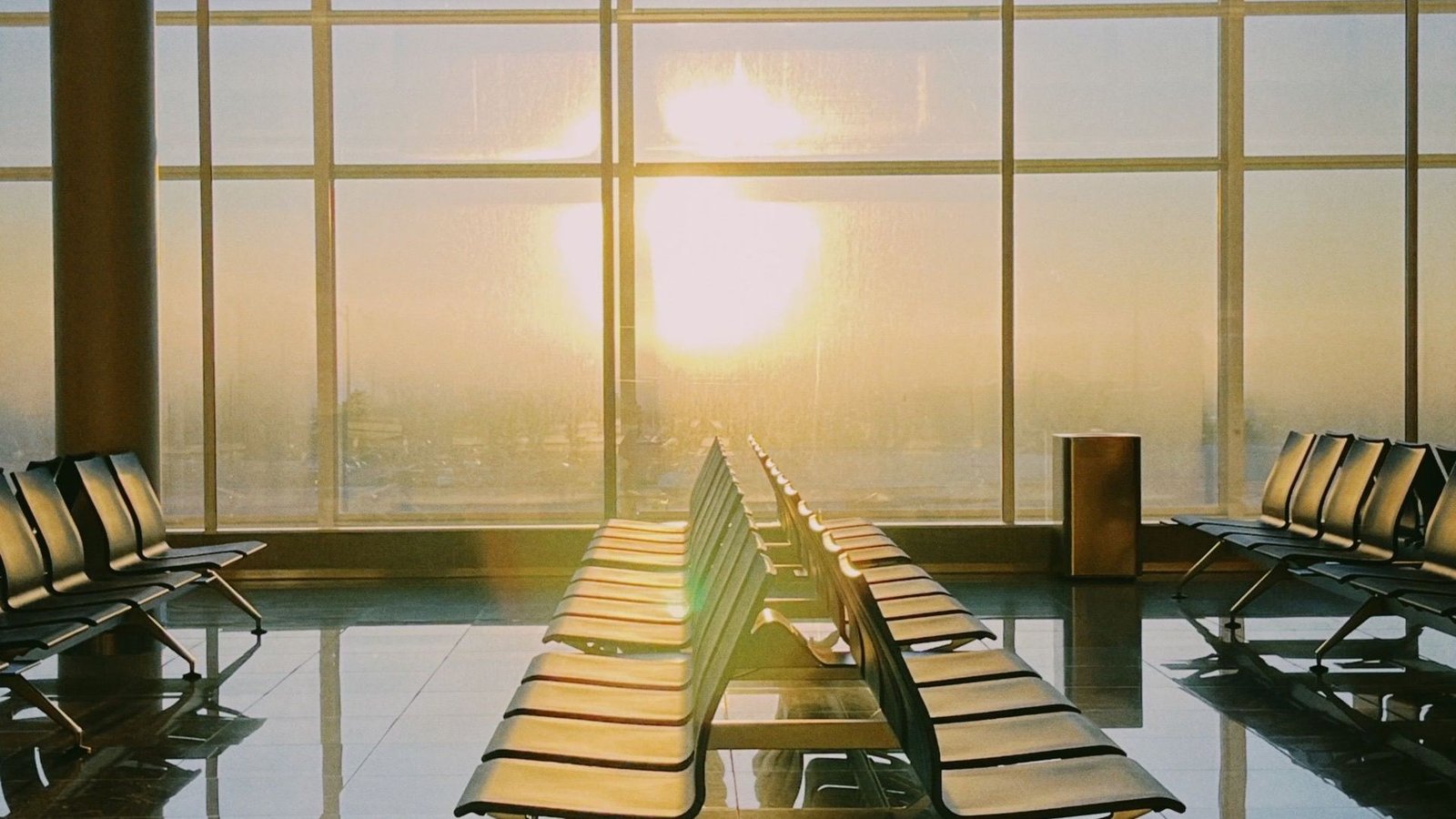 Empty terminal seating in front of tall windows at sunset