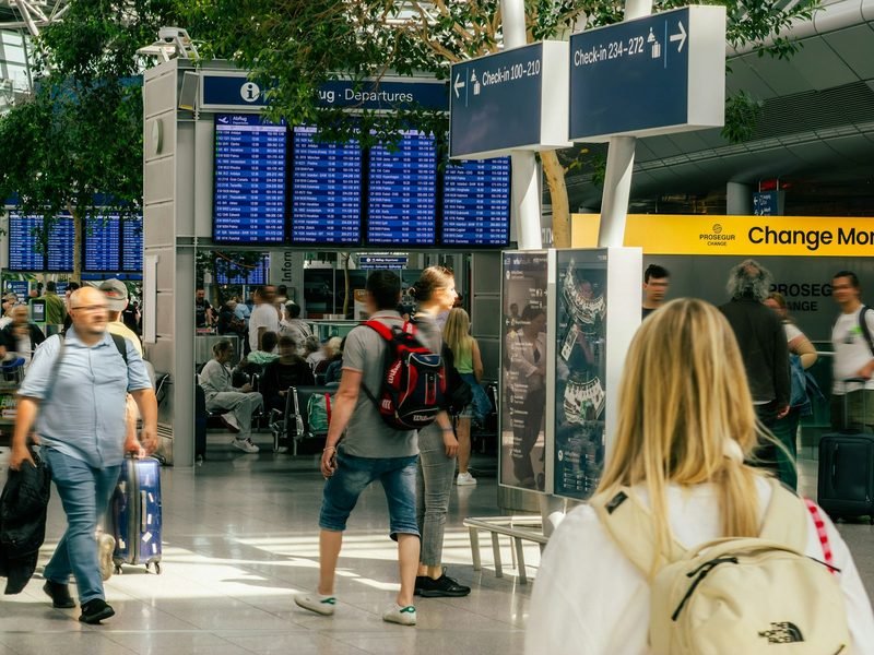 Passengers crossing an airport terminal past the departures board