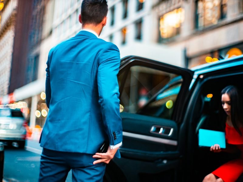 A passenger in a suit beside a waiting car