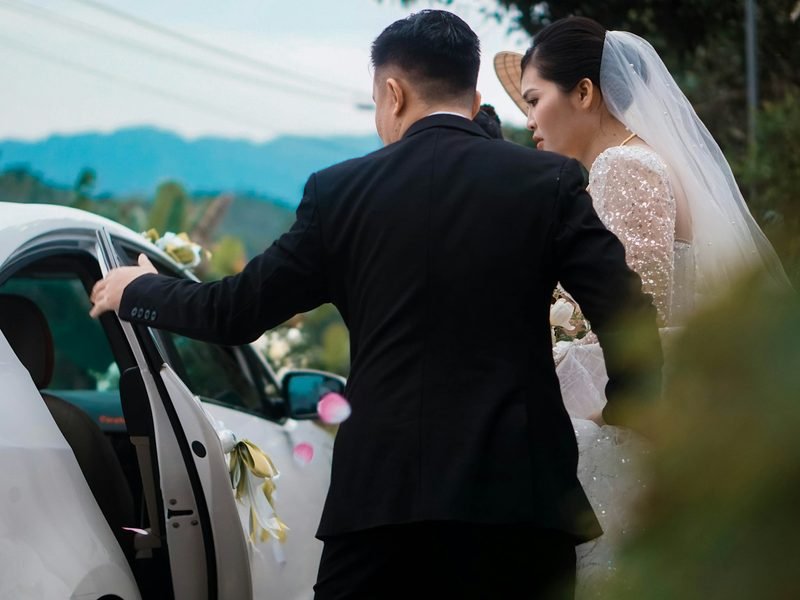 A groom holding the car door open for the bride